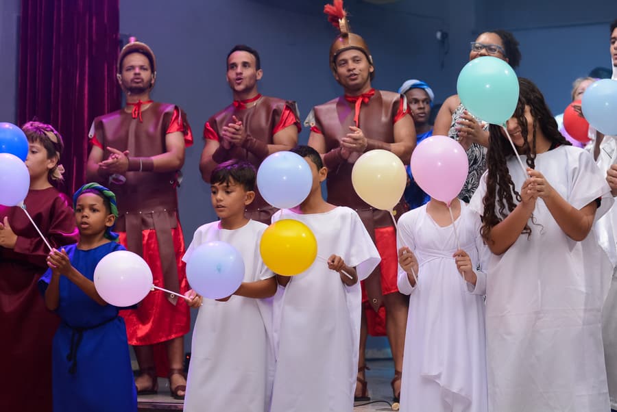 Crianças do Ministério Infantil no palco da igreja, segurando balões coloridos