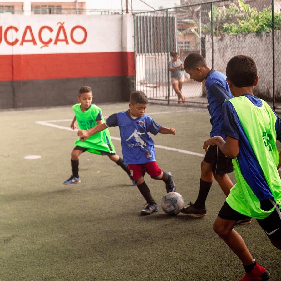 Crianças disputando a bola durante um treino de futebol do ministério esportivo